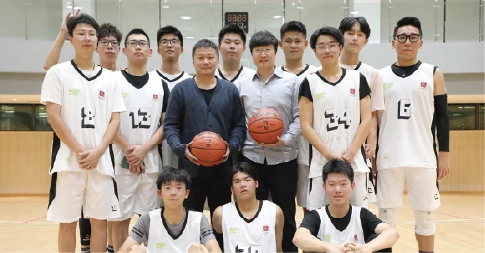 Basketball players and their coach pose together in the gym.